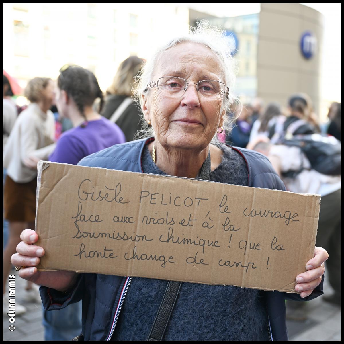 Au rassemblement en soutien à Gisèle Pelicot et aux victimes de VSS, une femme retraitée blanche tient une pancarte "Gisèle Pelicot, le courage face aux viols et à la soumission chimique. la honte doit changer de camp"
