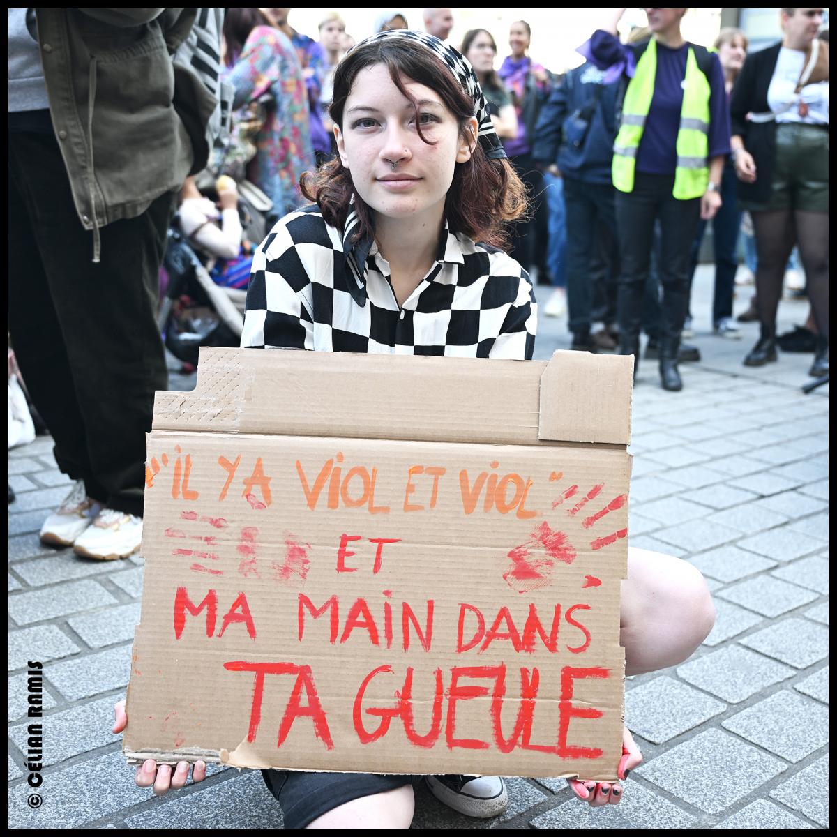 Au rassemblement en soutien à Gisèle Pelicot et aux victimes de VSS, une jeune militante blanche tient une pancarte "Il y a viol et viol et ma main dans ta gueule"